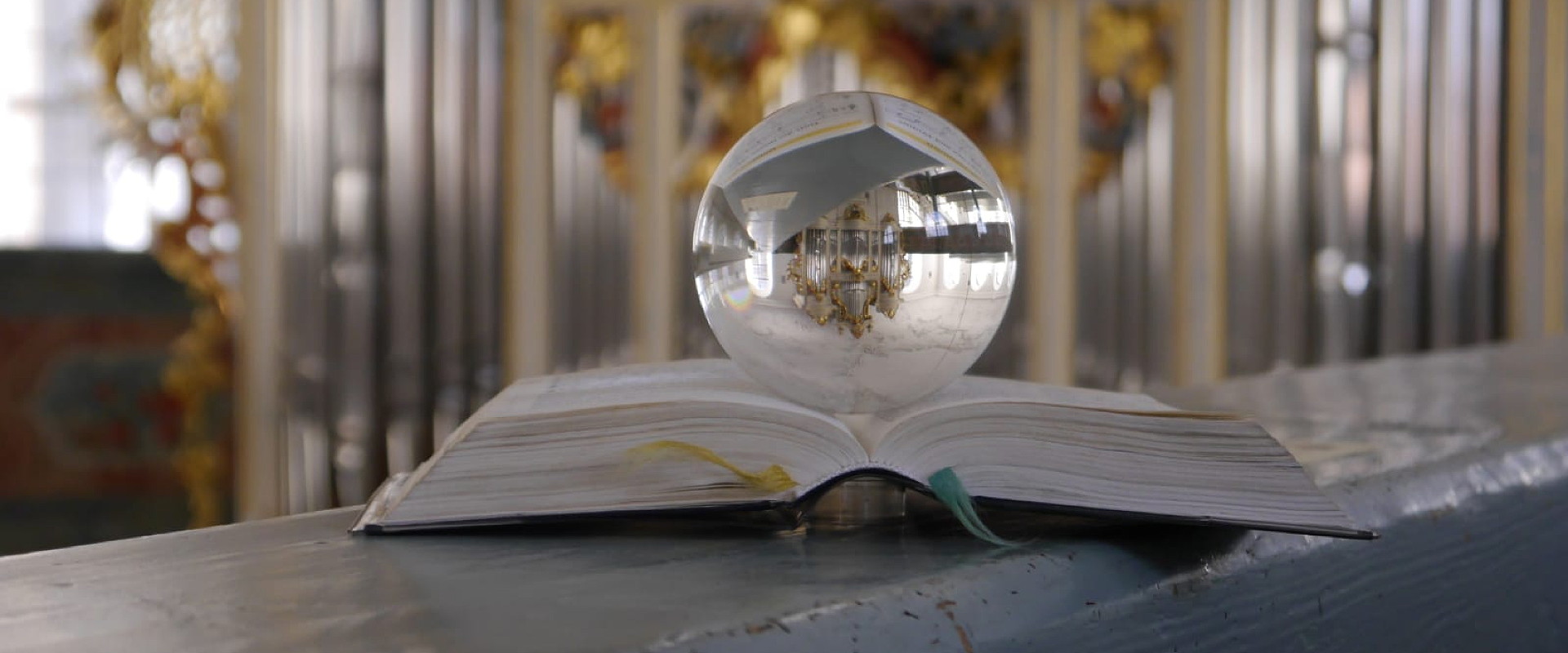 Glaskugel mit Durchsicht zur gespiegelter Orgel auf Gesangsbuch liegend - Foto von Uli Löffler
